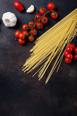 İtalyan makarnası pişirmek için gerekenler: spagetti, domates ve siyah masada sarımsak. Fotokopi alanı olan en üst görüntü