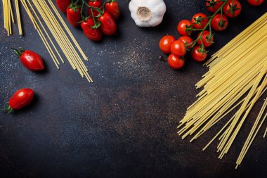 İtalyan makarnası pişirmek için gerekenler: spagetti, domates ve siyah masada sarımsak. Fotokopi alanı olan en üst görüntü