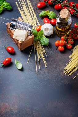 İtalyan yemeği kavramı: spagetti, domates, fesleğen, sarımsak, peynir ve siyah masadaki zeytinyağı. Kopyalama alanı olan üst görünüm