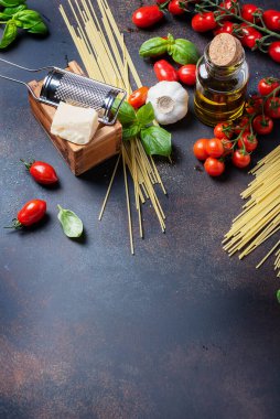 İtalyan yemeği kavramı: spagetti, domates, fesleğen, sarımsak, peynir ve siyah masadaki zeytinyağı. Kopyalama alanı olan üst görünüm