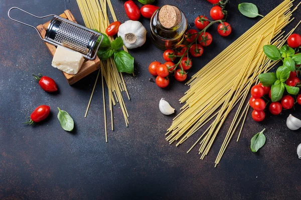 İtalyan yemeği kavramı: spagetti, domates, fesleğen, sarımsak, peynir ve siyah masadaki zeytinyağı. Kopyalama alanı olan üst görünüm