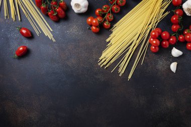 İtalyan makarnası pişirmek için gerekenler: spagetti, domates ve siyah masada sarımsak. Fotokopi alanı olan en üst görüntü