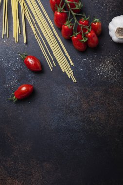 İtalyan makarnası pişirmek için gerekenler: spagetti, domates ve siyah masada sarımsak. Fotokopi alanı olan en üst görüntü