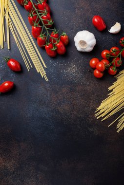 İtalyan makarnası pişirmek için gerekenler: spagetti, domates ve siyah masada sarımsak. Fotokopi alanı olan en üst görüntü