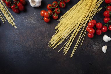 İtalyan makarnası pişirmek için gerekenler: spagetti, domates ve siyah masada sarımsak. Fotokopi alanı olan en üst görüntü