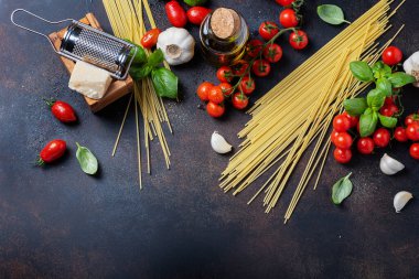 İtalyan yemeği kavramı: spagetti, domates, fesleğen, sarımsak, peynir ve siyah masadaki zeytinyağı. Kopyalama alanı olan üst görünüm