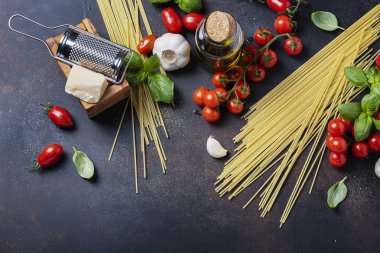 İtalyan yemeği kavramı: spagetti, domates, fesleğen, sarımsak, peynir ve siyah masadaki zeytinyağı. Kopyalama alanı olan üst görünüm