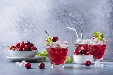 Bar konsepti. Blu gri arka planda kiraz, buz ve nane aromalı yaz alkollü kokteyl. Seçici odak resmi