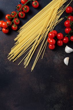 İtalyan makarnası pişirmek için gerekenler: spagetti, domates ve siyah masada sarımsak. Fotokopi alanı olan en üst görüntü