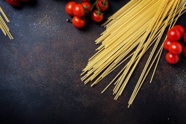 İtalyan makarnası pişirmek için gerekenler: spagetti, domates ve siyah masada sarımsak. Fotokopi alanı olan en üst görüntü