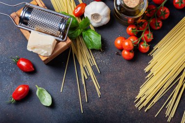 İtalyan yemeği kavramı: spagetti, domates, fesleğen, sarımsak, peynir ve siyah masadaki zeytinyağı. Kopyalama alanı olan üst görünüm