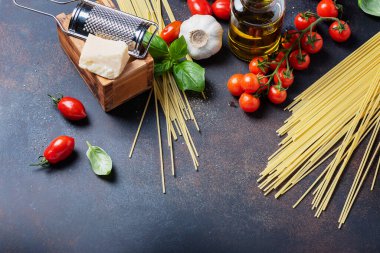 İtalyan yemeği kavramı: spagetti, domates, fesleğen, sarımsak, peynir ve siyah masadaki zeytinyağı. Kopyalama alanı olan üst görünüm