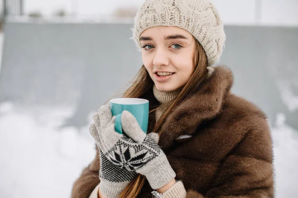 Kadın içecekler sıcak çay veya açık havada karlı kış sabahı sıcacık bir fincan kahve. Güzel kız sıcak içecek bir fincan bir bahçeye kışın tadını çıkarıyor. Noel tatili