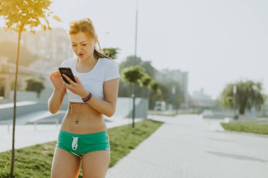 Fitness runner kadın doğanın içinde smartphone üzerinde söz.