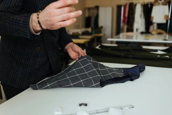 Young male tailor sewing fabric at table in fashion studio