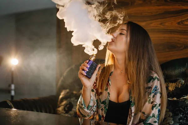 Seksi sekreter e-sigara ve ofiste vapurla masada oturuyor.