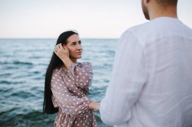 Kumsalda bir erkeğin elini tutan bir kız..