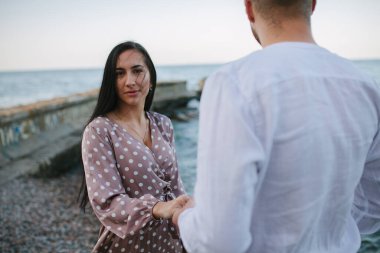 Kumsalda bir erkeğin elini tutan bir kız..