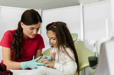 Kız dişçi ofisinde gösterir nasıl dişlerinizi fırçalamak için