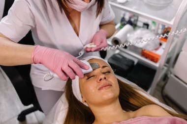 Ultrasonik süzgeç. Yüzün ultrasonik temizlenmesi prosedürü. Model, profil. Kozmetik kliniği. Sağlık, klinik, kozmetoloji