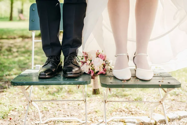 特写新娘和新郎脚站在椅子上新娘花束之间 — 图库照片