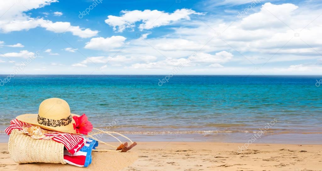 sunbathing accessories on sandy beach in straw bag