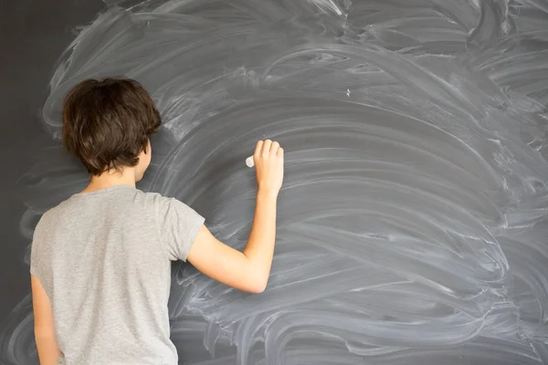 Boy writting on black board — Stok Foto