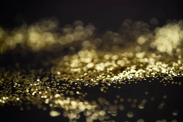 Bellissimo sfondo luce di Natale. Bokeh glitter astratto e scintille sparse in oro, su nero — Foto Stock