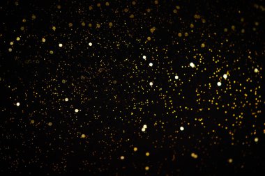 Güzel bir Noel ışığı arka planı. Soyut parıltı bokeh ve saçılmış altın parıltıları, siyah üzerine