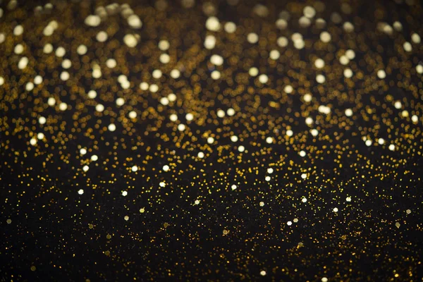 Beautiful Christmas light background. Abstract glitter bokeh and scattered sparkles in gold, on black — Stock Photo, Image