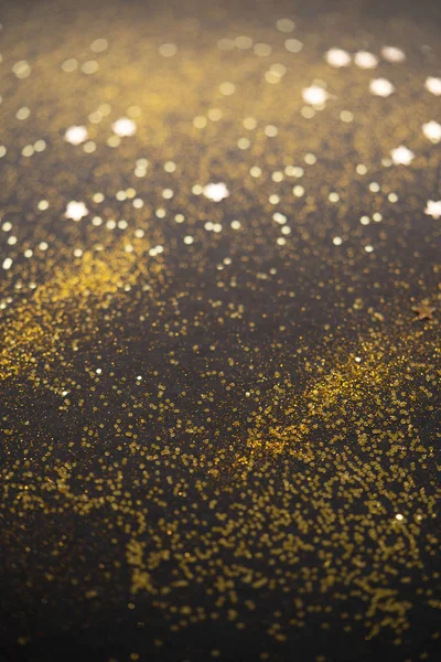 Bellissimo sfondo luce di Natale. Bokeh glitter astratto e scintille sparse in oro, su nero — Foto Stock