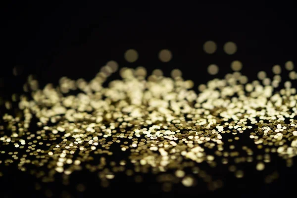 Mooie kerst lichte achtergrond. Abstract glitter bokeh en verspreide glitters in goud, op zwart — Stockfoto