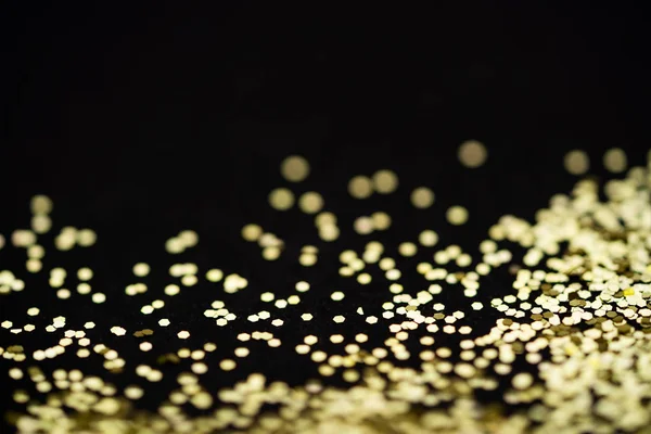 Vacker jul ljus bakgrund. Abstrakt glitter bokeh och spridda gnistrar i guld, på svart — Stockfoto