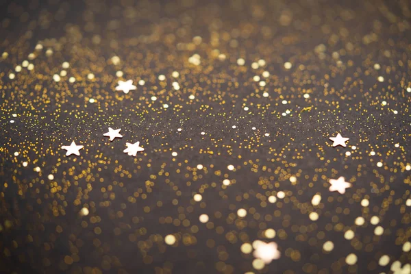 Hermoso fondo de luz de Navidad. Bokeh brillo abstracto y destellos dispersos en oro, en negro —  Fotos de Stock