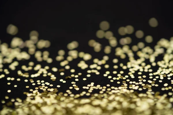 Beautiful Christmas light background. Abstract glitter bokeh and scattered sparkles in gold, on black — Stock Photo, Image
