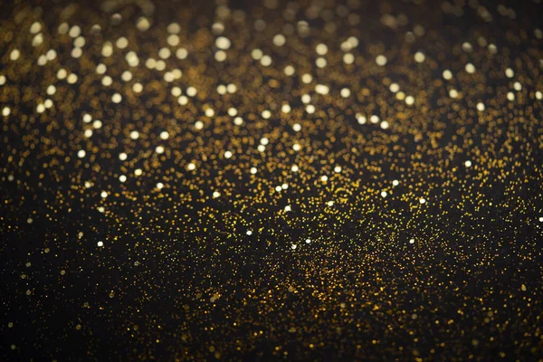 Hermoso fondo de luz de Navidad. Bokeh brillo abstracto y destellos dispersos en oro, en negro — Foto de Stock