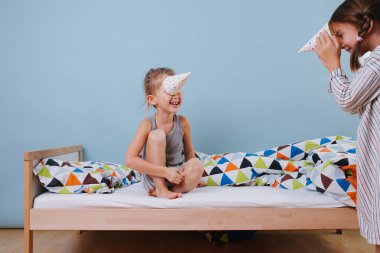 Erkek ve kız yatak odasında parti konisi şapkalarıyla oynuyorlar, boynuz gibi takıyorlar.