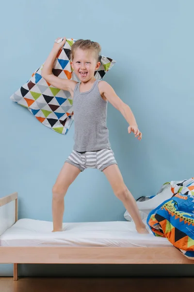 Küçük çocuk, mavi duvarlar üzerinde yastık savaşı için hazır. — Stok fotoğraf