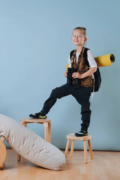Porträtt av en liten pojke med kikare klättra pall, leka vandrare hemma — Stockfoto