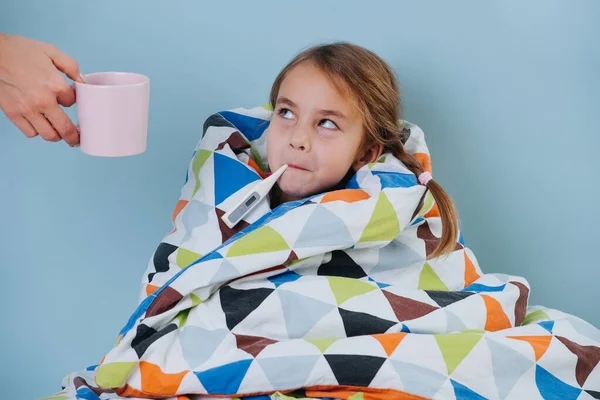 Petite fille malade avec le froid commun enveloppé dans la couverture, la température de mesure . — Photo