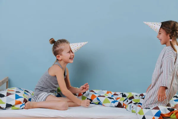 Menino e menina brincando no quarto com chapéus de cone de festa, vestindo-os como chifres — Fotografia de Stock