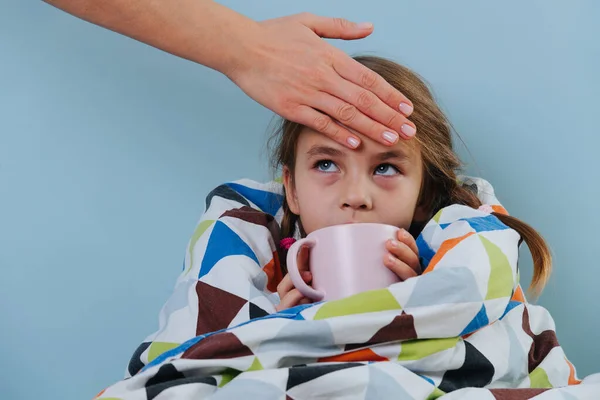Больная маленькая девочка с обычной простудой сидит в постели под одеялом с теплым чаем — стоковое фото