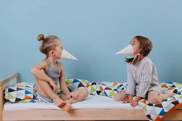 Niño y niña jugando en el dormitorio con sombreros de cono de fiesta, usándolos como picos —  Fotos de Stock