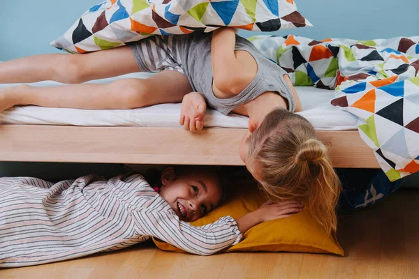 Маленький хлопчик і дівчинка грають у спальні. Дівчина лежить під ліжком, хлопчик дивиться на неї — стокове фото