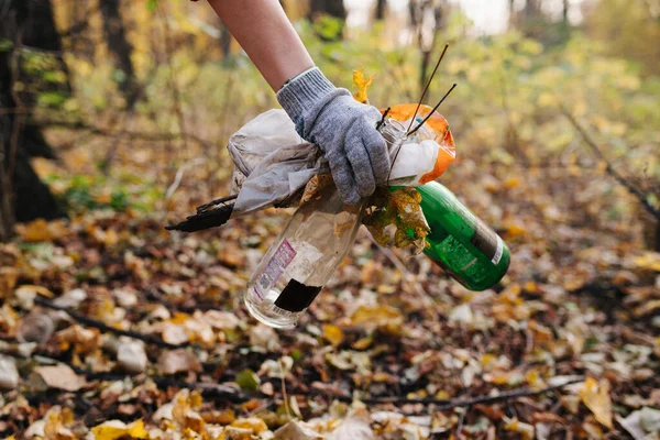 Primer plano de la mano femenina recogiendo un montón de basura del suelo del bosque . — Foto de Stock