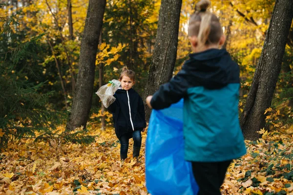 Hermanos pequeños recogiendo basura juntos en un bosque estacional en otoño — Foto de Stock