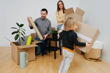 Genç bir aile yeni bir eve taşındı. Karton kutuları birlikte açıyorlar.