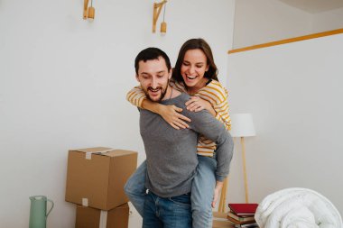Çift yeni bir daireye taşınmayı kutluyor. Bir kadın erkeğinin sırtında.