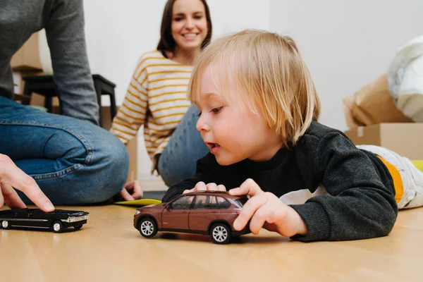 Joyeux jeune famille déménageant dans une nouvelle maison, garçon jouant avec des jouets dans une nouvelle maison — Photo