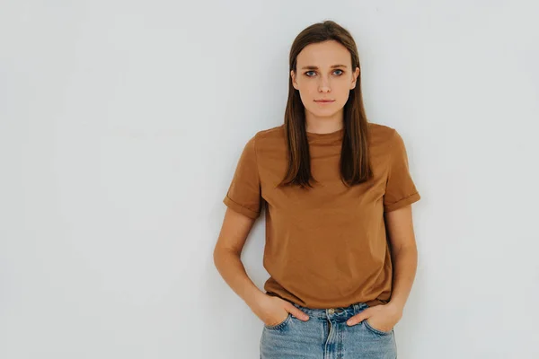 Portrait of a woman, leaning on the wall, with hands in pockets. Half length — ストック写真